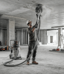 Oztec ceiling grinder smoothing overhead concrete ceiling surface during construction project